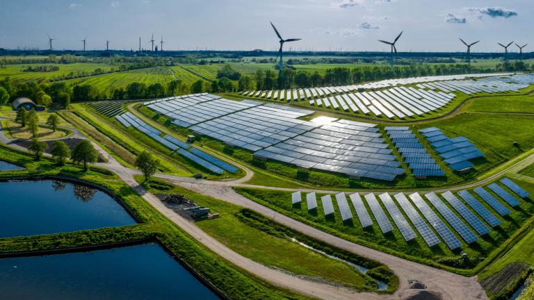 A field full of solar panels and wind turbines