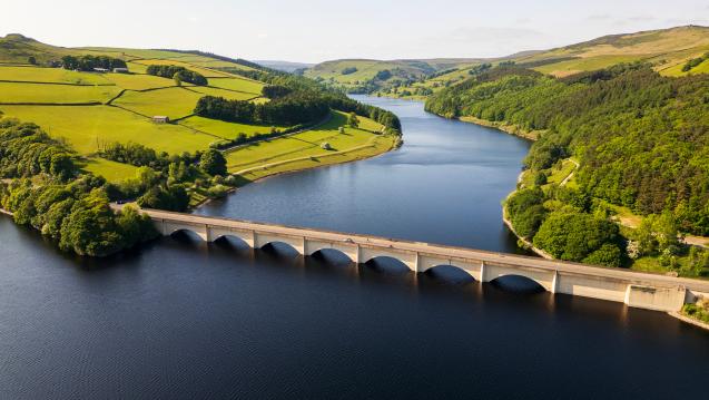 Landscape photo of hills bisected by a river, connected by a bridge